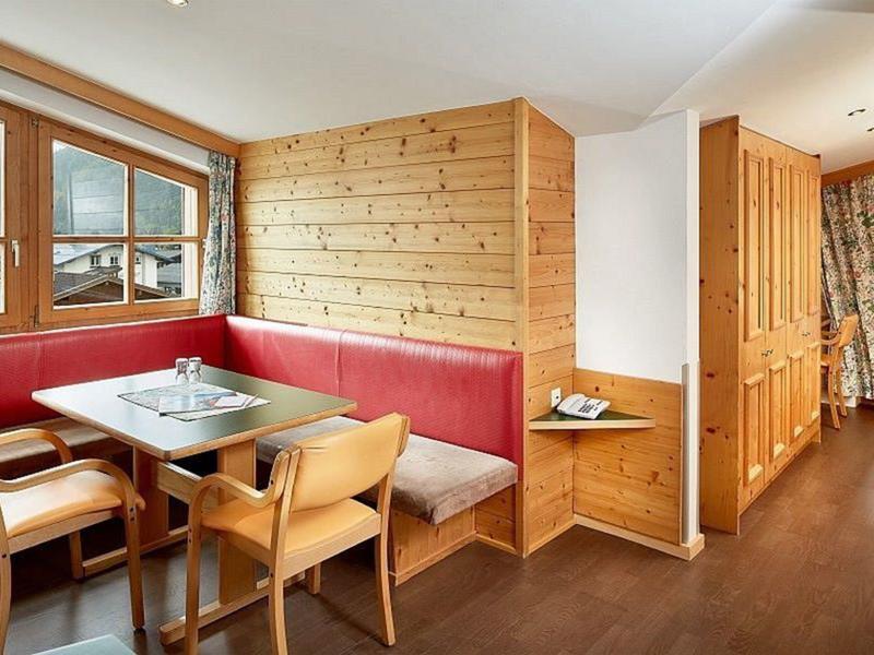 Gemütliche Holzecke mit rotem Polstersofa, Holztisch und Stühlen, hell und einladend.