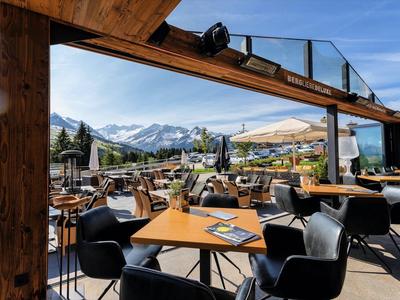 Terraza de hotel con mesas, sillas y vista a la montaña bajo cielo despejado