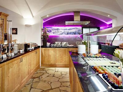 Zona de buffet de hotel con madera cálida, mostradores modernos e iluminación púrpura