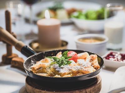 Bowl of Kaiserschmarrn garnished with powdered sugar and berries on a set table.