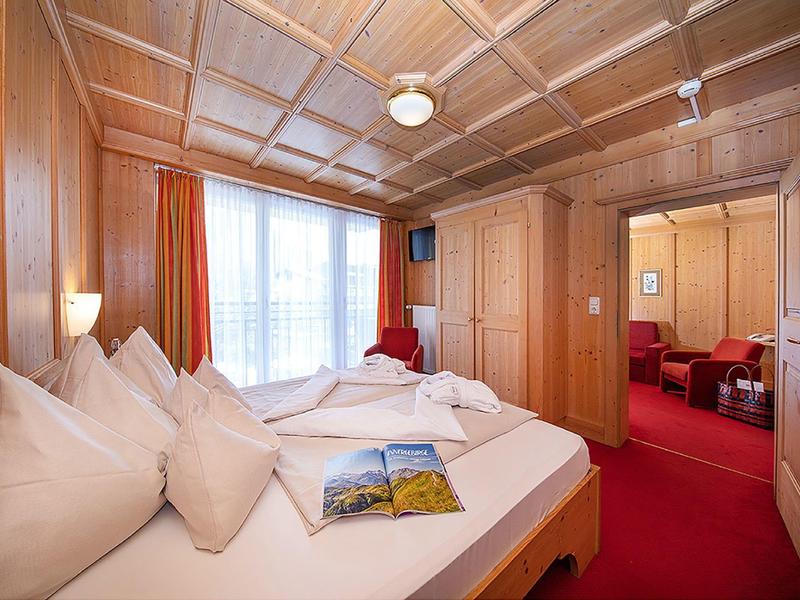 Gemütliches Schlafzimmer mit Holzwänden, rotem Teppich und großem Bett mit weißen Kissen.