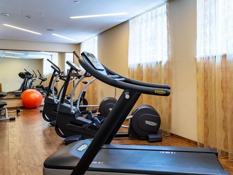 Moderner Fitnessraum mit Laufbändern, Fahrradergometern und Gymnastikball, hell und sauber.