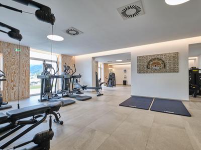 Moderní posilovna s vybavením, velkými okny a jasným osvětlením v hotelu.