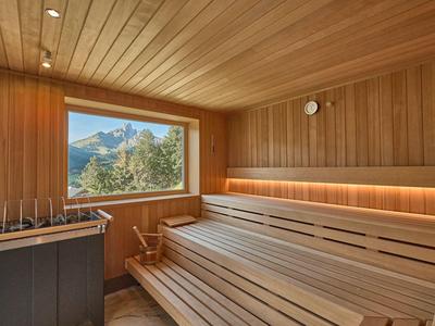 Eine helle finnische Sauna aus hellem Holz mit großer Fensterfront und Bergblick.