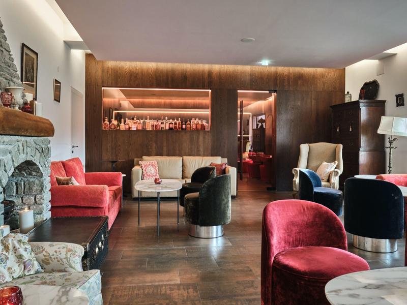 Gemütlicher Wohnzimmerbereich mit rotem und schwarzem Polster, Kamin und dunklem Holzboden.