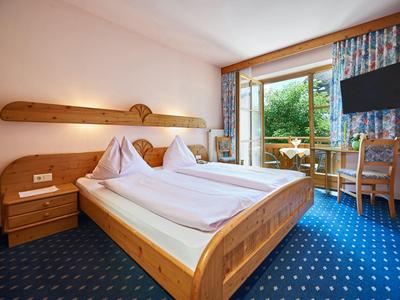 Bright hotel room with wooden beds, balcony, and blue carpet.