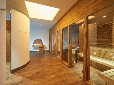 Moderner Wellnessraum mit Sauna, Holzverkleidung, großen Glastüren und gemütlicher Beleuchtung.