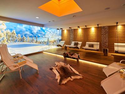 Moderner Wellnessraum mit Holzfußboden, Liegestühlen, Kamin und großer Fensterwand.