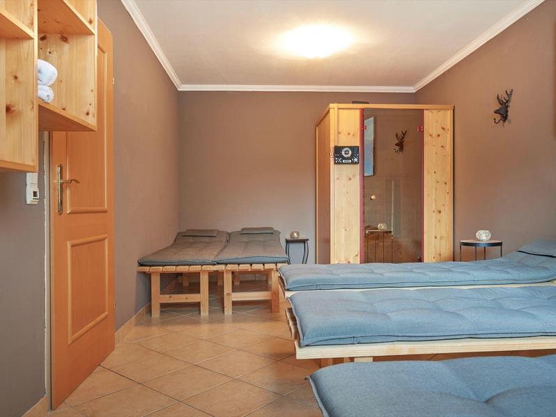 Schlichtes Zimmer mit Holzbetten, blauer Bettwäsche, Kachelfußboden und braun gestrichenen Wänden.