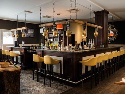 Bar d'hôtel confortable avec bois foncé et tabourets jaunes