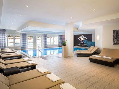 Moderner Wellnessbereich mit Pool, bequemen Liegen und heller, freundlicher Gestaltung.