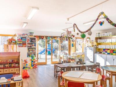 Světla a barevná herna pro děti se stoly, hračkami a dekoracemi.