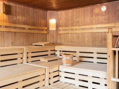 Interiér finské sauny s dřevěnými lavicemi, kýblem a naběračkou.