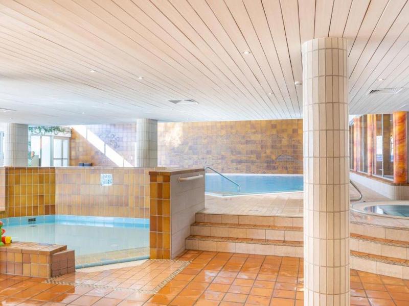 Vnitřní wellness se dvěma bazény a světlými dlaždicovými podlahami.