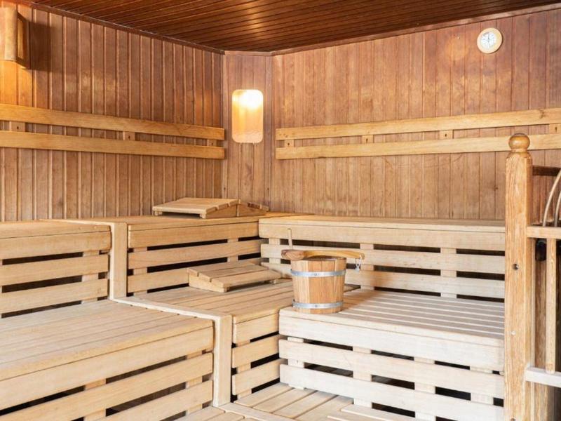 Interiér finské sauny s dřevěnými lavicemi, kýblem a naběračkou.
