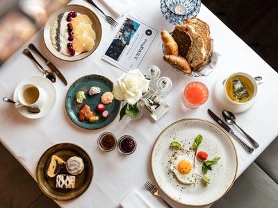 Elegant breakfast with eggs, croissants, juice, and coffee served on a white table.
