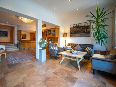 Gezellige hotel loungeruimte met banken, hout- en steenelementen en een grote plant.