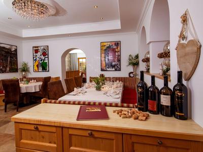 Un elegante comedor con muebles de madera, botellas de vino y una lámpara de araña en el techo.