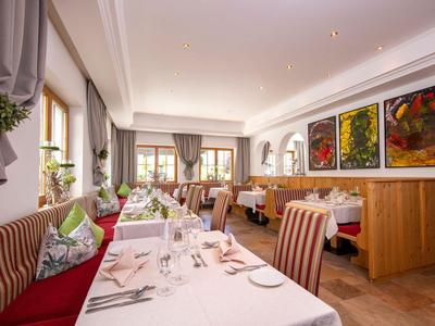 Restaurante elegante con manteles blancos y sillas tapizadas junto a ventanas y paredes de madera.