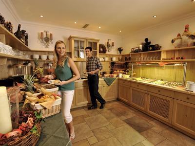 Kleine Bäckerei mit Holzmöbeln, frischem Gebäck, Regalen voll mit Brot und zwei Gästen beim Einkaufen.