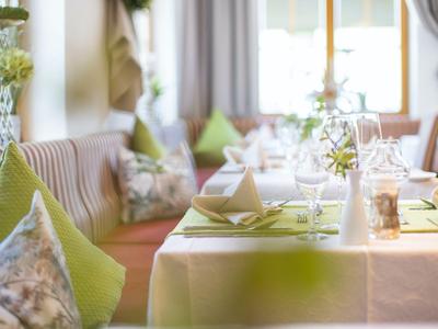 Mesa bien puesta en un restaurante con cojines verdes en los bancos
