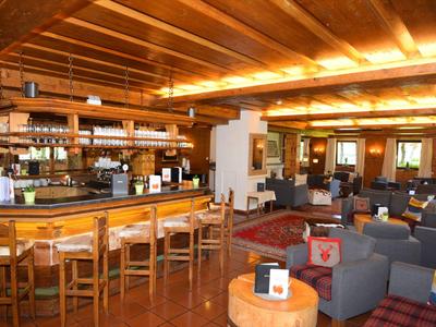 Bar d'hôtel accueillante avec mobilier en bois et plusieurs espaces de sièges sous un éclairage chaleureux.