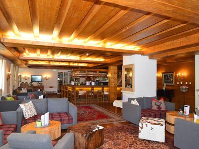 Espace salon d'hôtel confortable avec plafond à poutres en bois et sièges confortables.