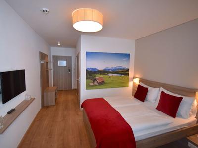 Modern eingerichtetes Hotelzimmer mit Doppelbett, Wandbild und Flachbildfernseher