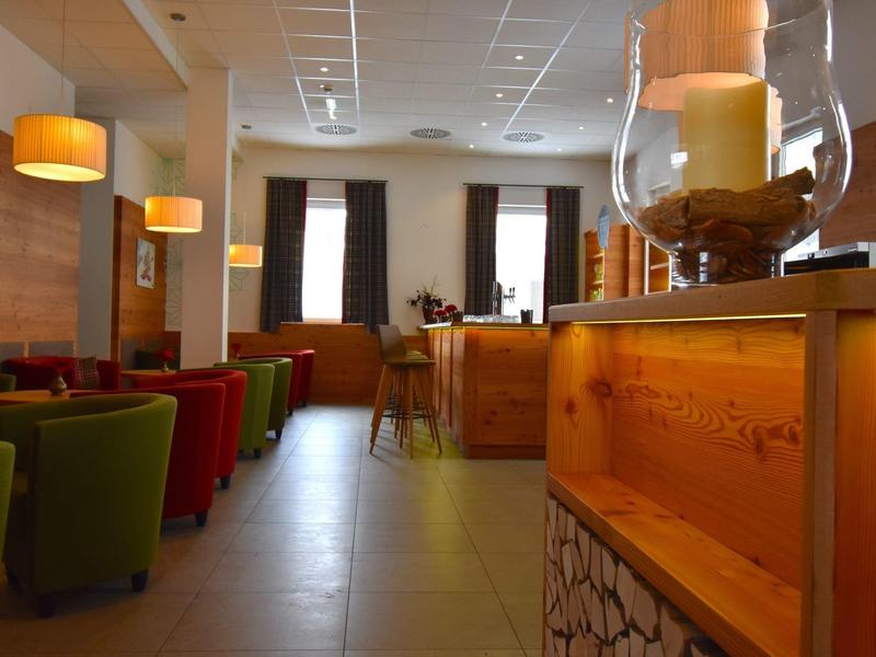 Espace lounge d'hôtel confortable avec des fauteuils colorés, mobilier en bois et éclairage doux.