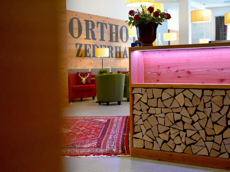 Espace de réception moderne avec décor en bois, tapis et sièges sous un éclairage chaleureux.