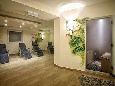 Moderner Wellnessraum mit Liegestühlen, Pflanzen und beleuchtetem Duschbereich.