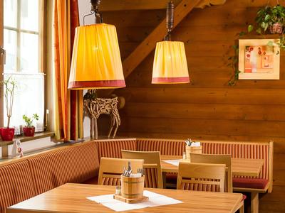 Gemütliche Hotel-Ecke mit Holzmöbeln, warmem Licht und Pflanzen an Fenster und Wand.
