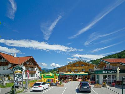 Bergdorf mit Restaurants, geparkten Autos und blauem Himmel mit Wolken im Urlaubsort.