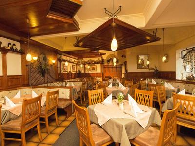 Elegantes Restaurant mit Holzmöbeln, weißen Tischdecken und warmem, einladendem Beleuchtungskonzept.