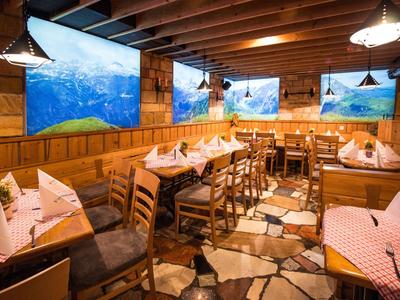 Rustikales Restaurant mit Holzwänden, gedeckten Tischen und Landschaftsbildern zur Dekoration.