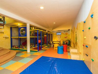 Bunter Indoor-Spielbereich mit Kletterwand und Spielgeräten in einem Hotel.