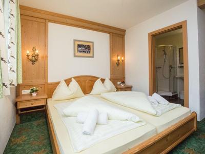 Ein gemütliches Hotelzimmer mit Doppelbett, Holzmöbeln und einem angrenzenden Badezimmer.