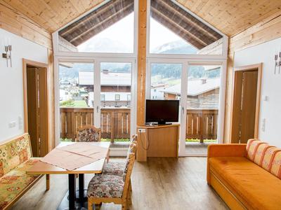 Helles Wohnzimmer mit Holzdecke, Sitzbereich, TV und Ausblick auf die Berge