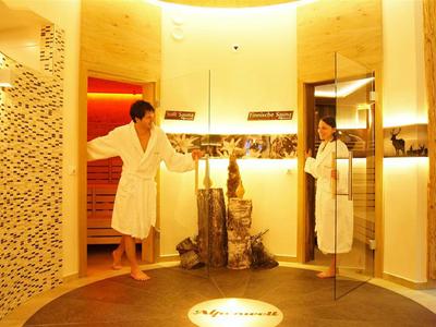 Zwei Personen im Bademantel in einem warm beleuchteten Spa-Bereich mit Sauna.