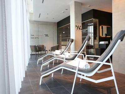 Trzy nowoczesne leżaki w jasnej strefie spa z dużymi oknami.