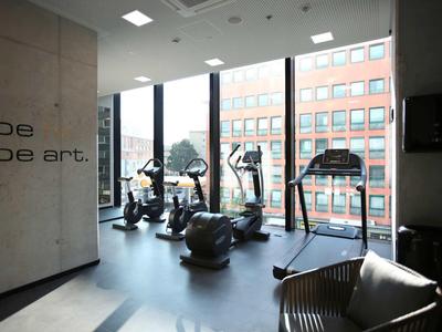 Nowoczesna siłownia z urządzeniami cardio i dużymi oknami z widokiem na zewnątrz.