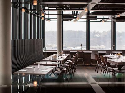 Elegancka hotelowa jadalnia z dużymi oknami i stylowymi drewnianymi meblami.