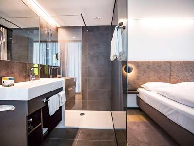 Nowoczesny pokój hotelowy z łazienką, szklaną prysznicem, łóżkiem i eleganckim oświetleniem