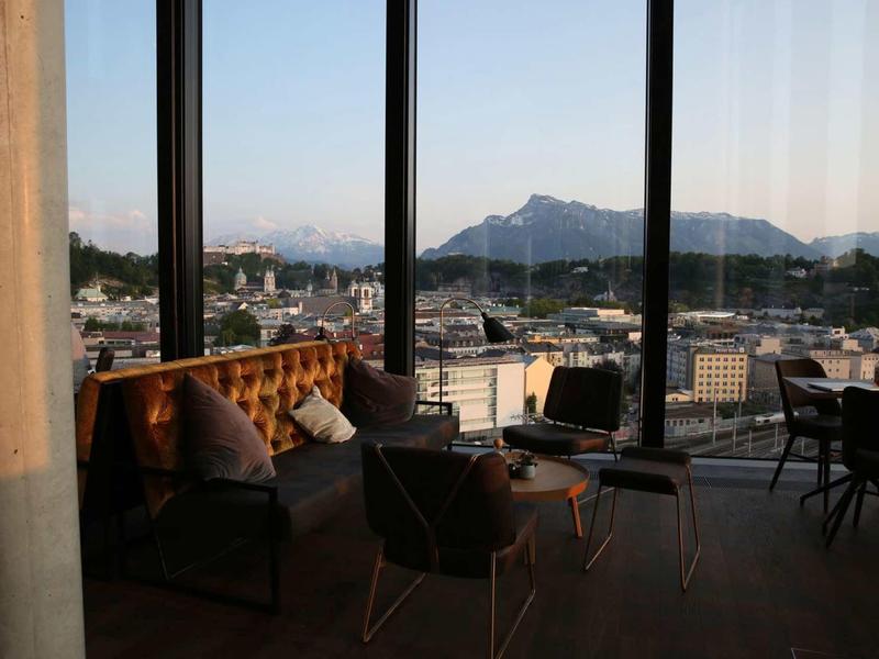 Duże okno z widokiem na góry i przytulny kącik wypoczynkowy w pokoju hotelowym.