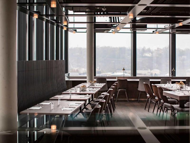 Elegancka hotelowa jadalnia z dużymi oknami i stylowymi drewnianymi meblami.