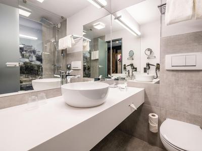 Modern hotel bathroom with white sink, mirrors, and toilet in a bright design.