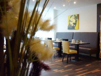 Gastronomiebereich mit Holzboden, Tischen, Stühlen und dekorativer Wandkunst.