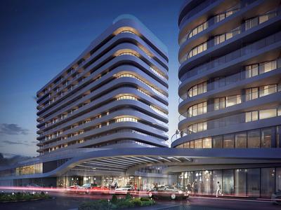 Modernes Hochhaus mit geschwungenen Linien, beleuchteten Fenstern und überdachtem Eingangsbereich bei Dämmerung.