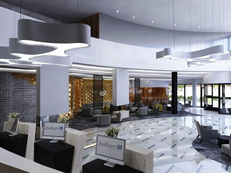 Moderne, helle Lobby mit weißen Sesseln, großem Empfangstresen und stilvollen Deckenleuchten.