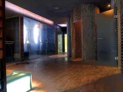 Moderner Raum mit Holz- und Glaswänden, warmem Licht und einem hohen, runden Säulenelement.